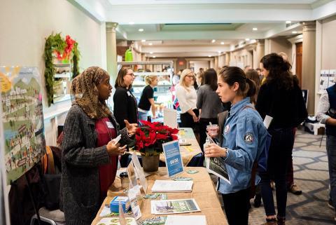 Food Solutions New England volunteer talking to student at tabling event.